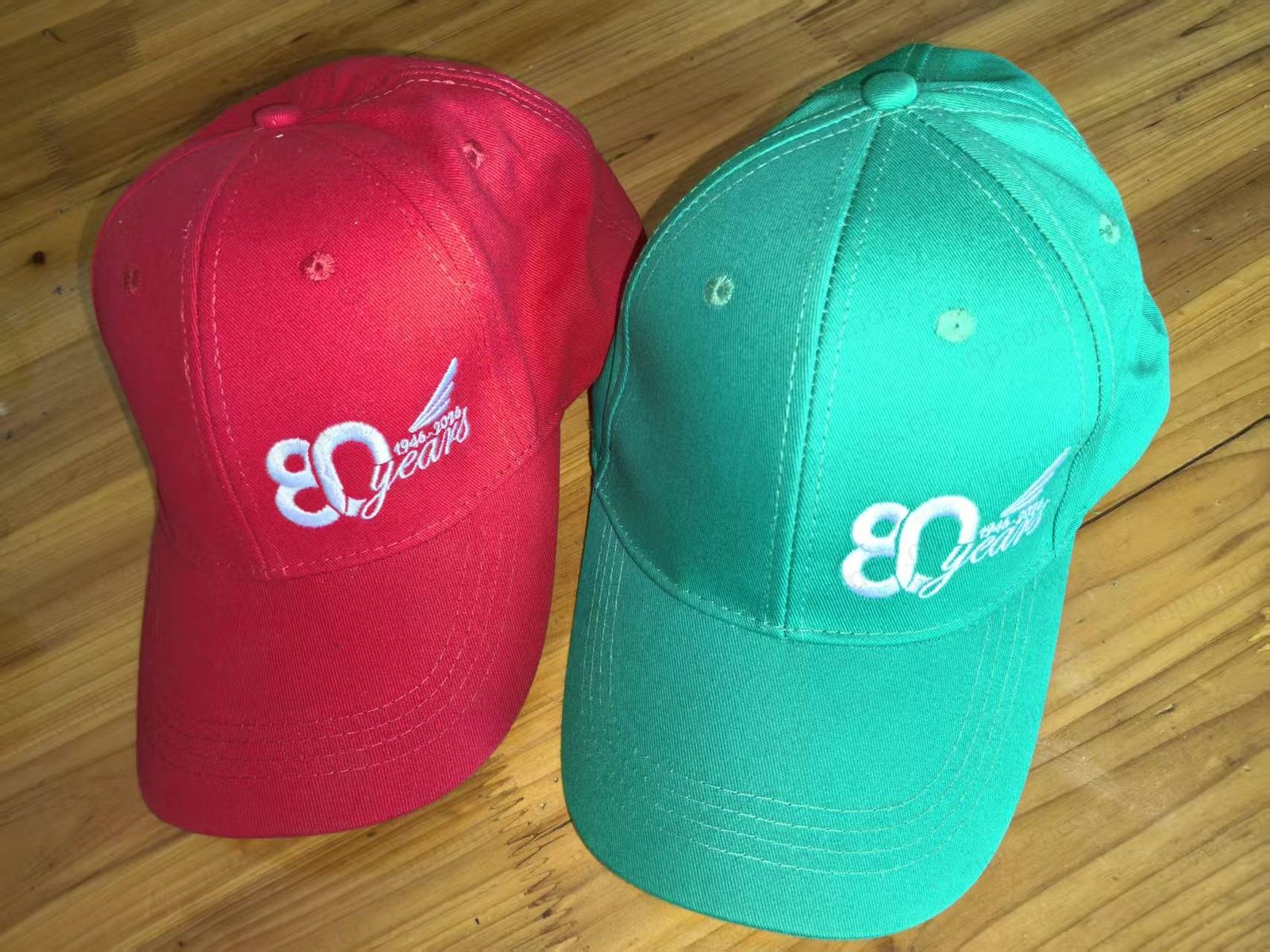 Red and green sport caps with 80 years embroidery — production photo